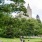 a group of people sitting in a park with trees and a castle in the background